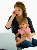 woman talking on cellphone and holding child on lap in front of laptop